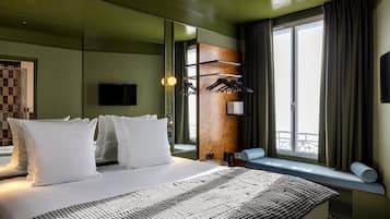 Habitación de hotel con una cama grande, televisión, ventana con vistas y un panel de madera en la pared.