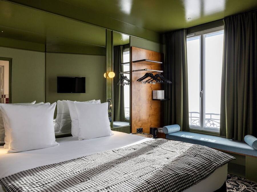 Habitación de hotel con una cama grande, televisión, ventana con vistas y un panel de madera en la pared.