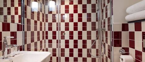 A bathroom with a checkered tile pattern, a glass shower enclosure, a sink, and a towel rack.