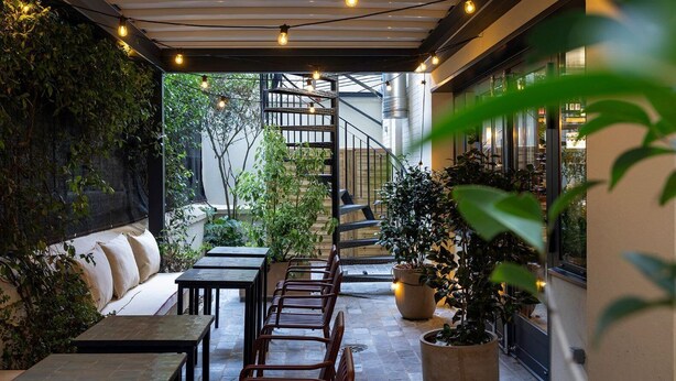 An outdoor patio area with tables and chairs, a staircase, and potted plants. - La Conversation (Paris)