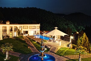 Un hotel con piscina, mobiliario exterior y una fuente.