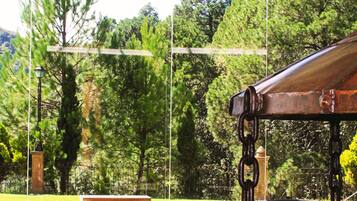 Un espacio de estar al aire libre techado, con vistas a un parque y árboles.