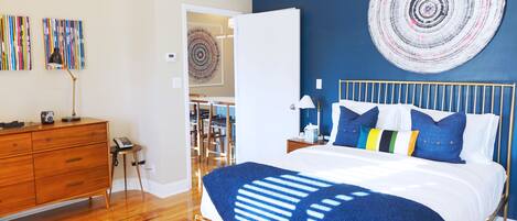 A bedroom with a bed, wooden dresser, and a wall with a circular artwork.