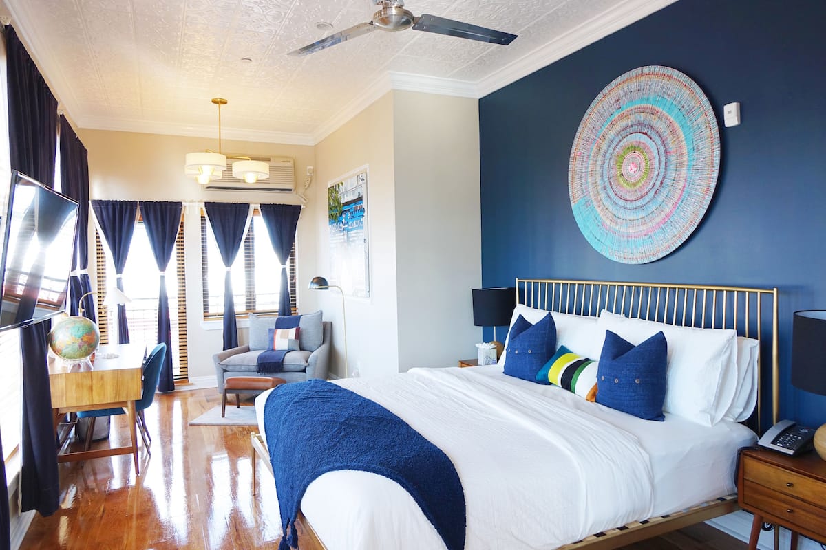 A well-lit bedroom with a bed, bedside tables, a desk, and a globe.