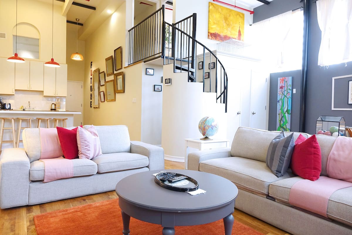 A modern living room with two sofas, a coffee table, and a staircase.