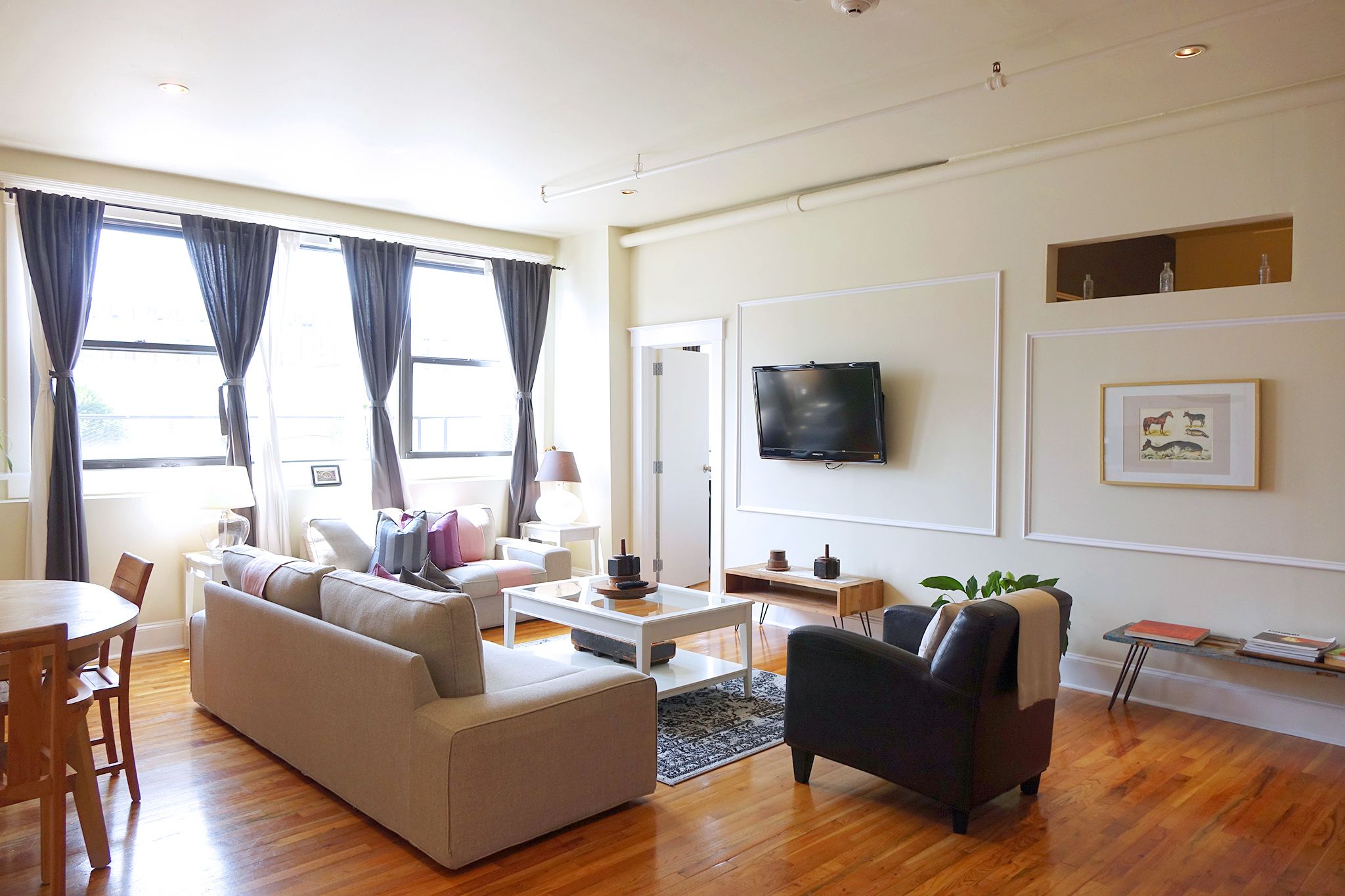 A modern living room with a sofa, coffee table, and a TV mounted on the wall.