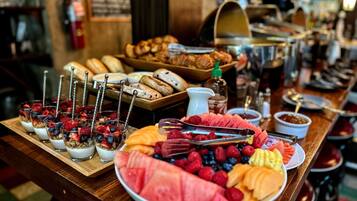 A breakfast buffet with various fruits, pastries, and a coffee station.