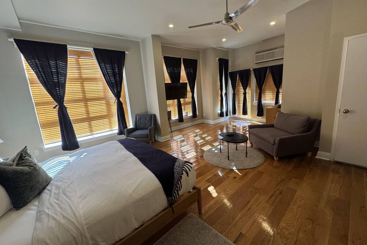 A spacious bedroom with a large bed, a sofa, a coffee table, and a ceiling fan.