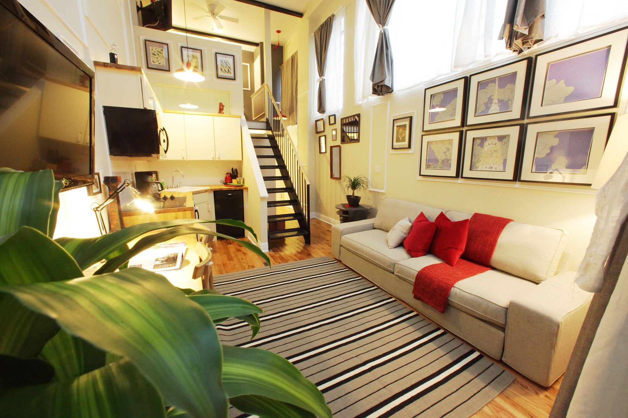 Un espacio habitable compacto con cocina, comedor y una escalera que lleva a un nivel superior.