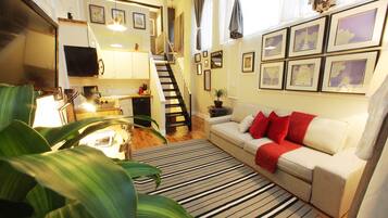 Un espacio habitable compacto con cocina, comedor y una escalera que lleva a un nivel superior.