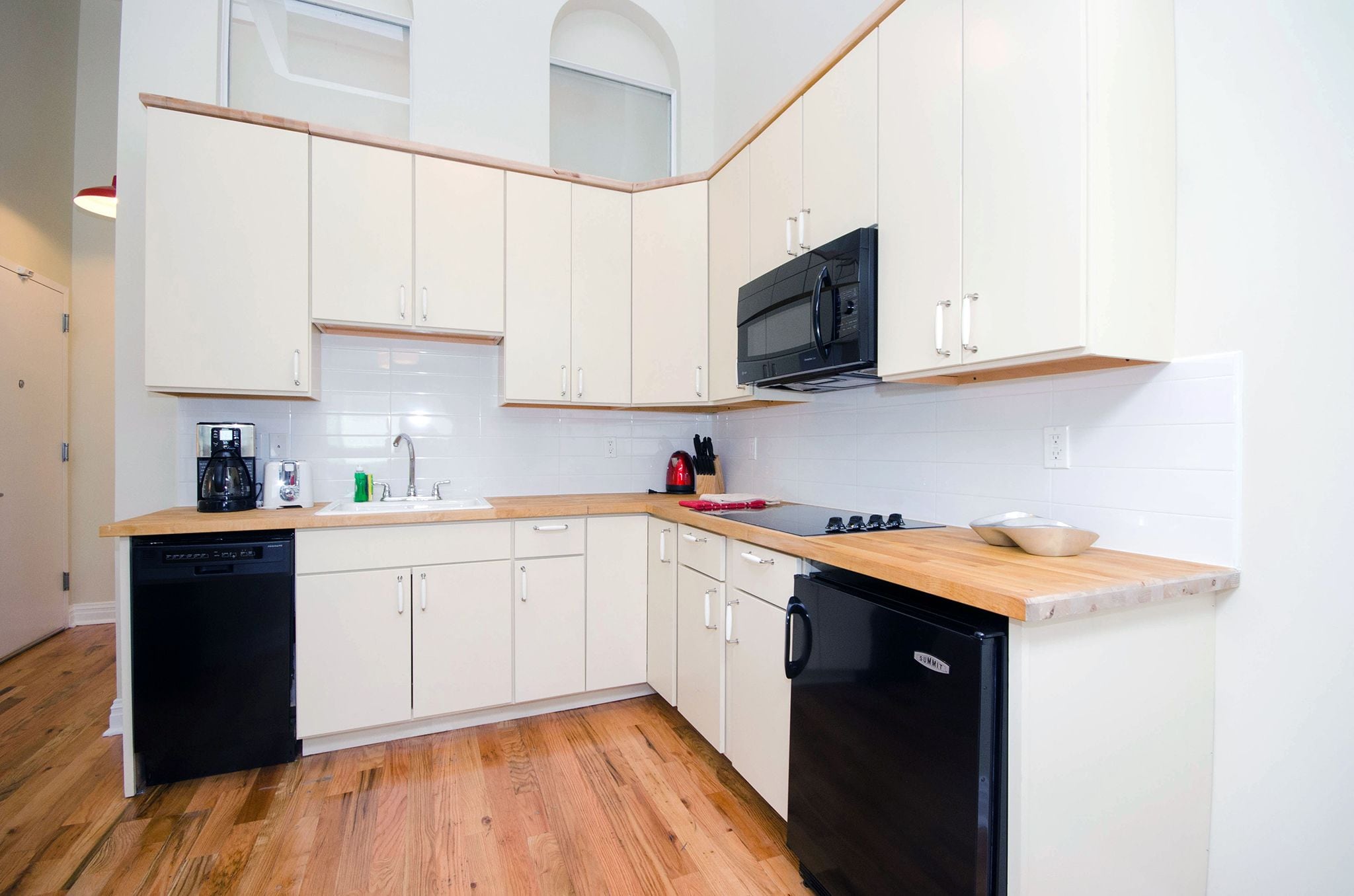 Una cocina moderna con armarios blancos, un microondas negro y un lavavajillas.