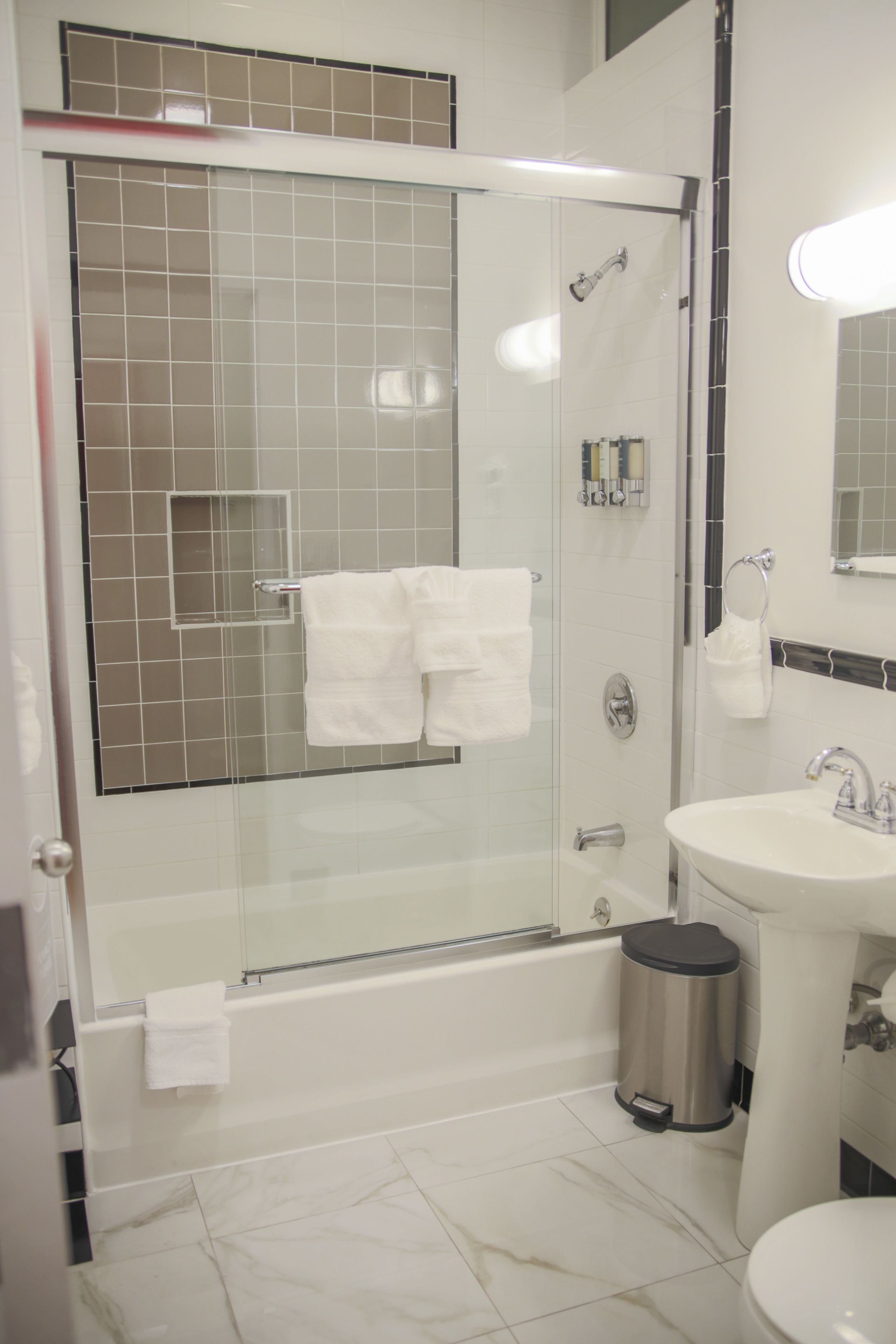 A modern bathroom with a glass-enclosed shower, a white sink, and a toilet.