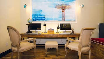 A wooden desk with two monitors, a globe, and a lamp.