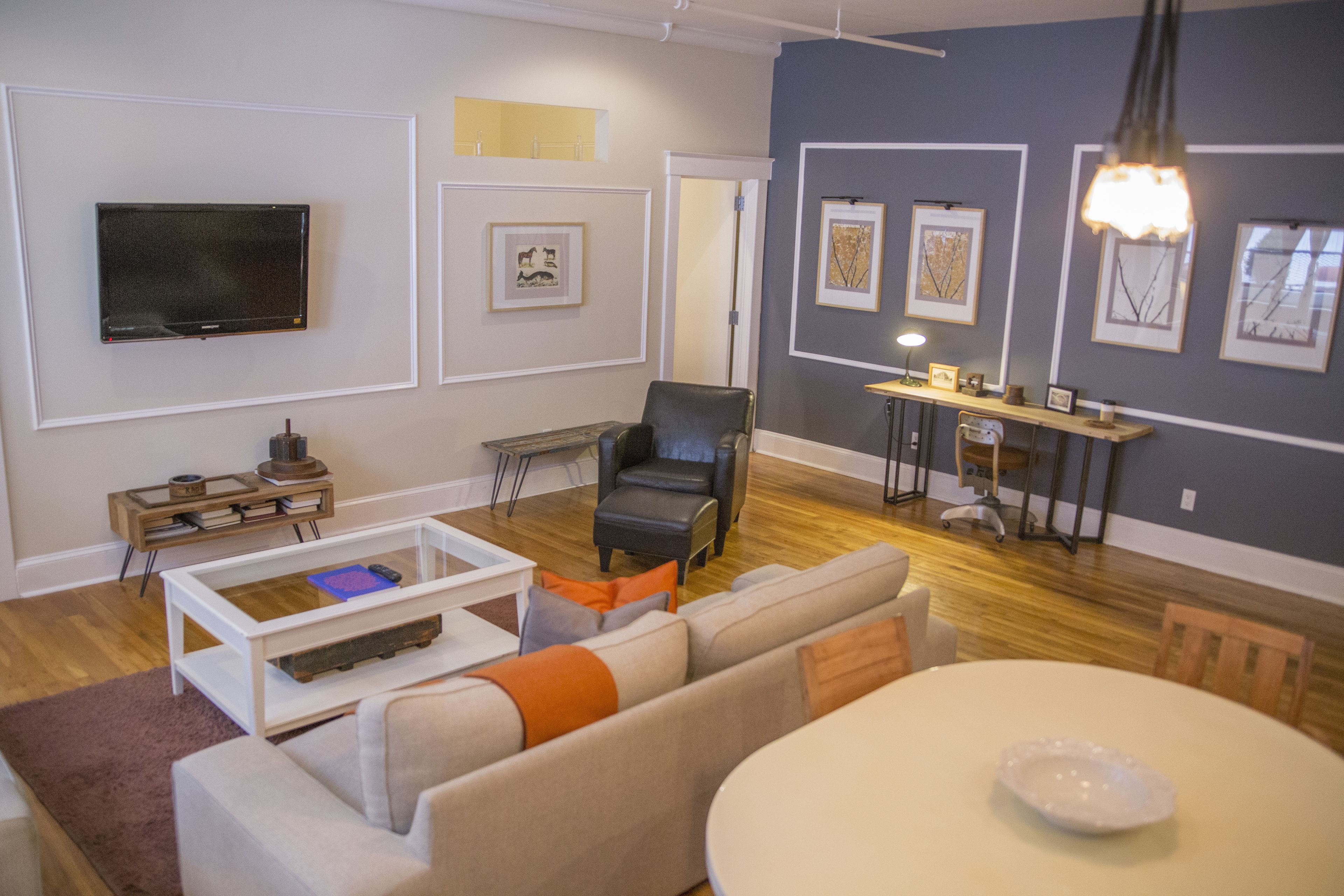 Una sala de estar moderna con una televisión de pantalla plana, un sofá, una mesa de centro y una mesa de comedor.