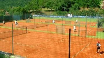 Un campo da tennis con diversi giocatori e una rete.