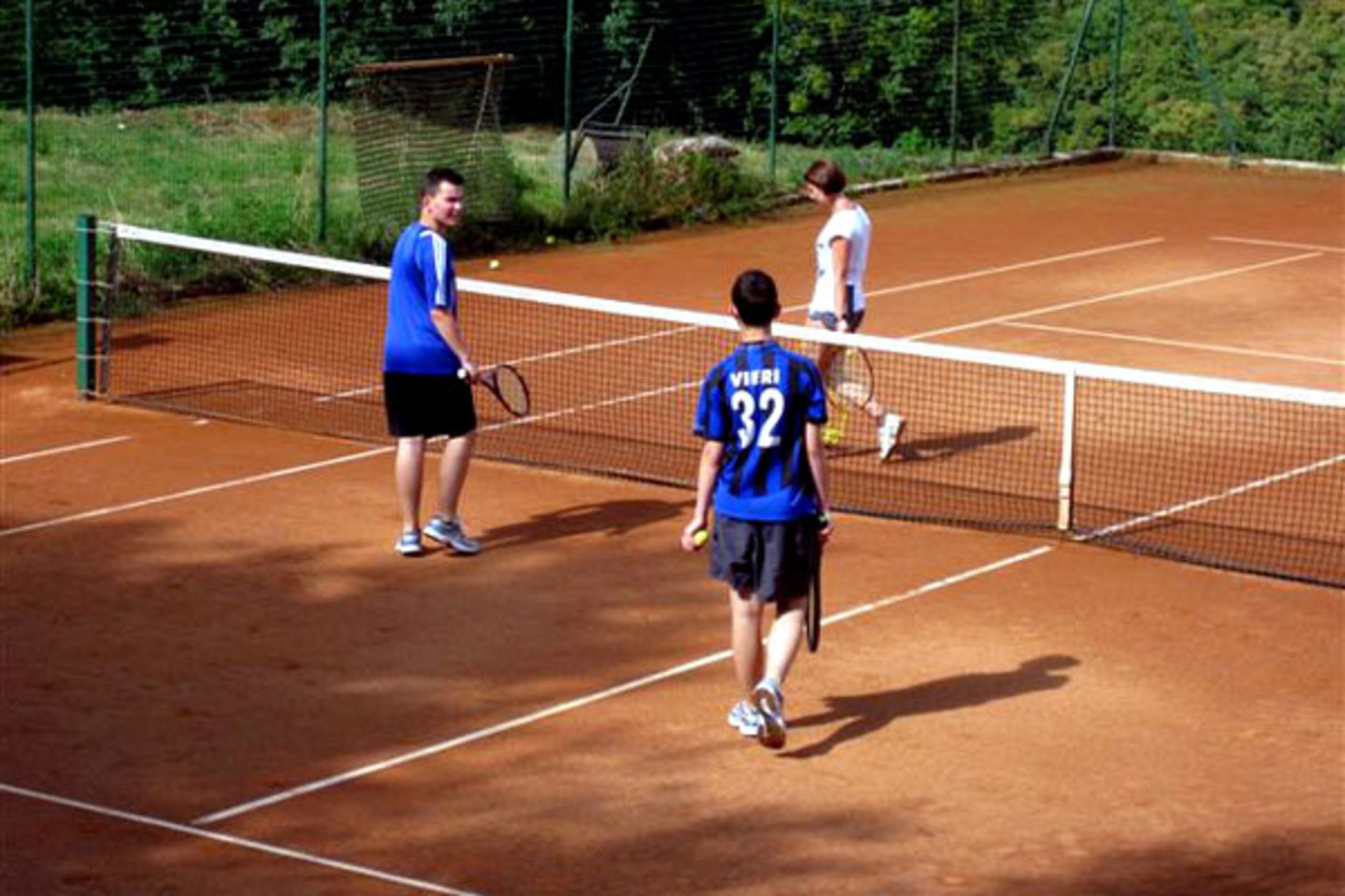 Un court de tennis avec un filet, des joueurs et un tableau d’affichage.