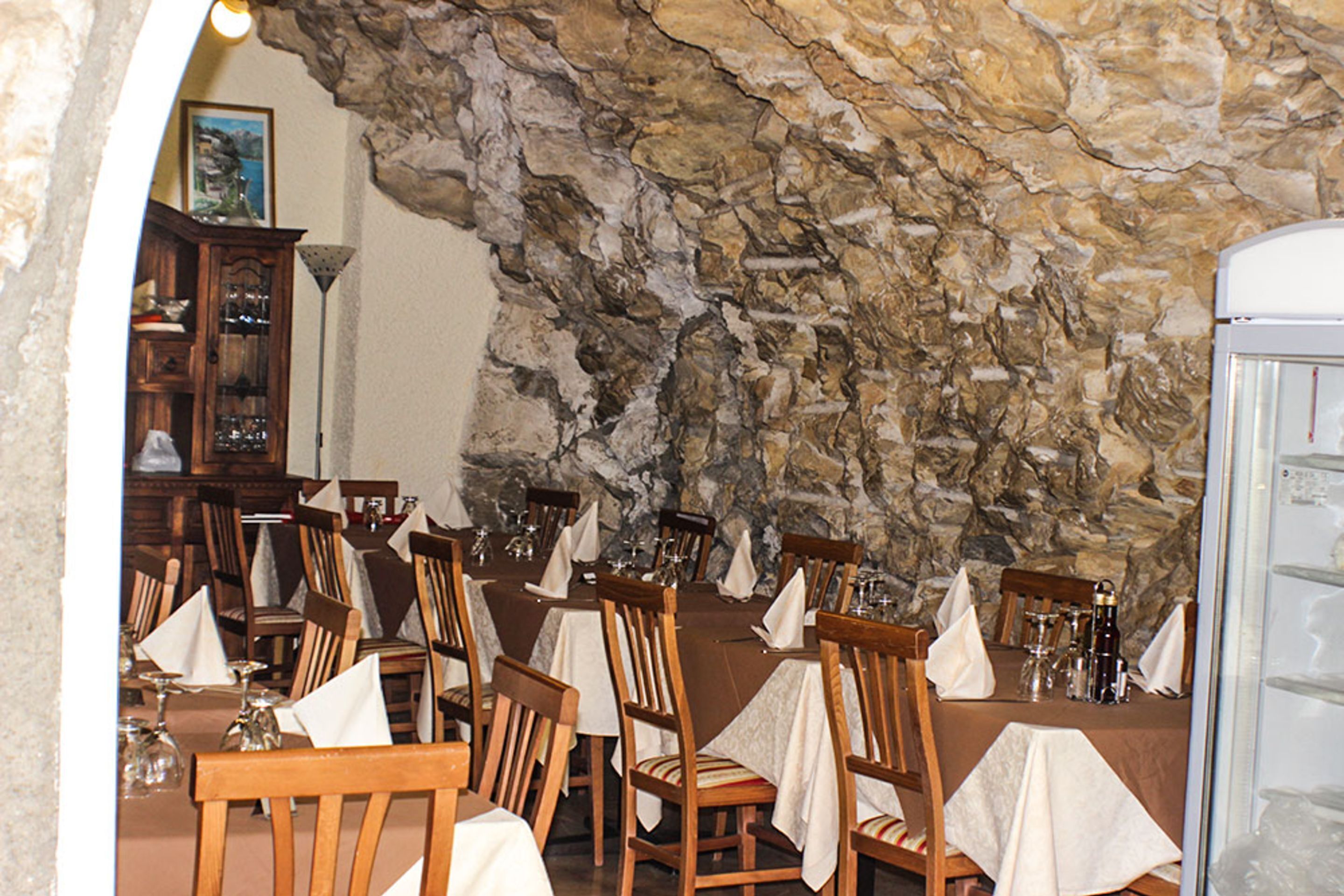 A restaurant with stone walls and wooden tables and chairs.