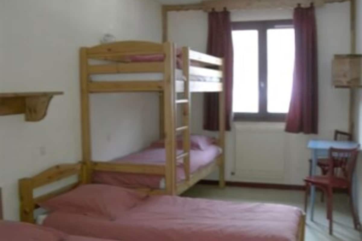 Una camera del dormitorio con letti a castello, una scrivania e una sedia.