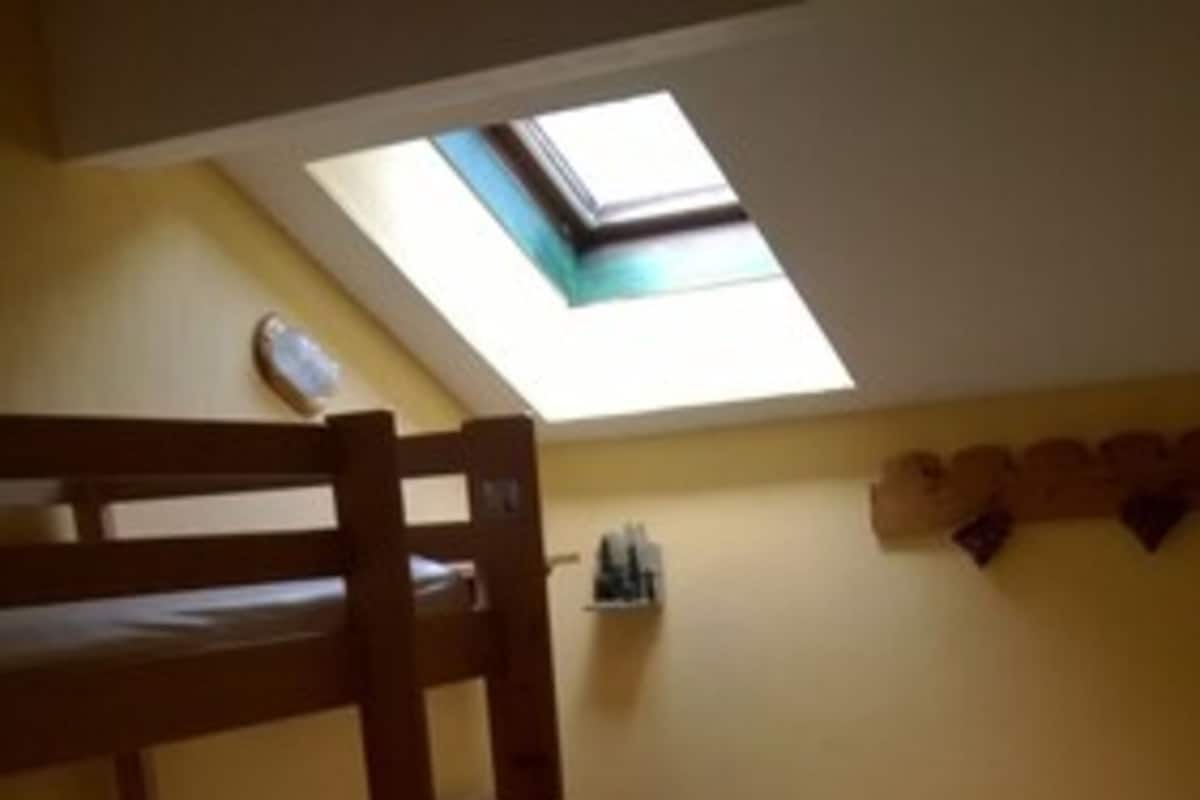 Una camera del dormitorio con letti a castello, un lucernario e un piccolo ripiano con articoli da toilette.