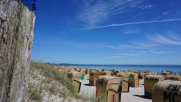 A beach with wicker beach chairs and a sandy area.