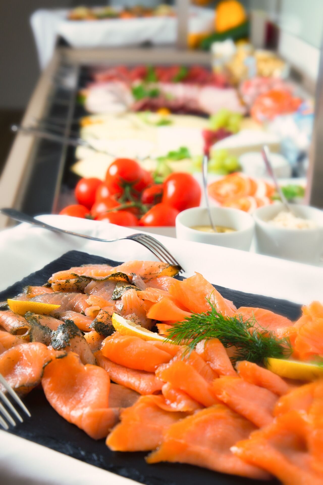A buffet with various dishes including salmon, tomatoes, and other foods.