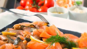 A buffet with various dishes including salmon, tomatoes, and other foods.