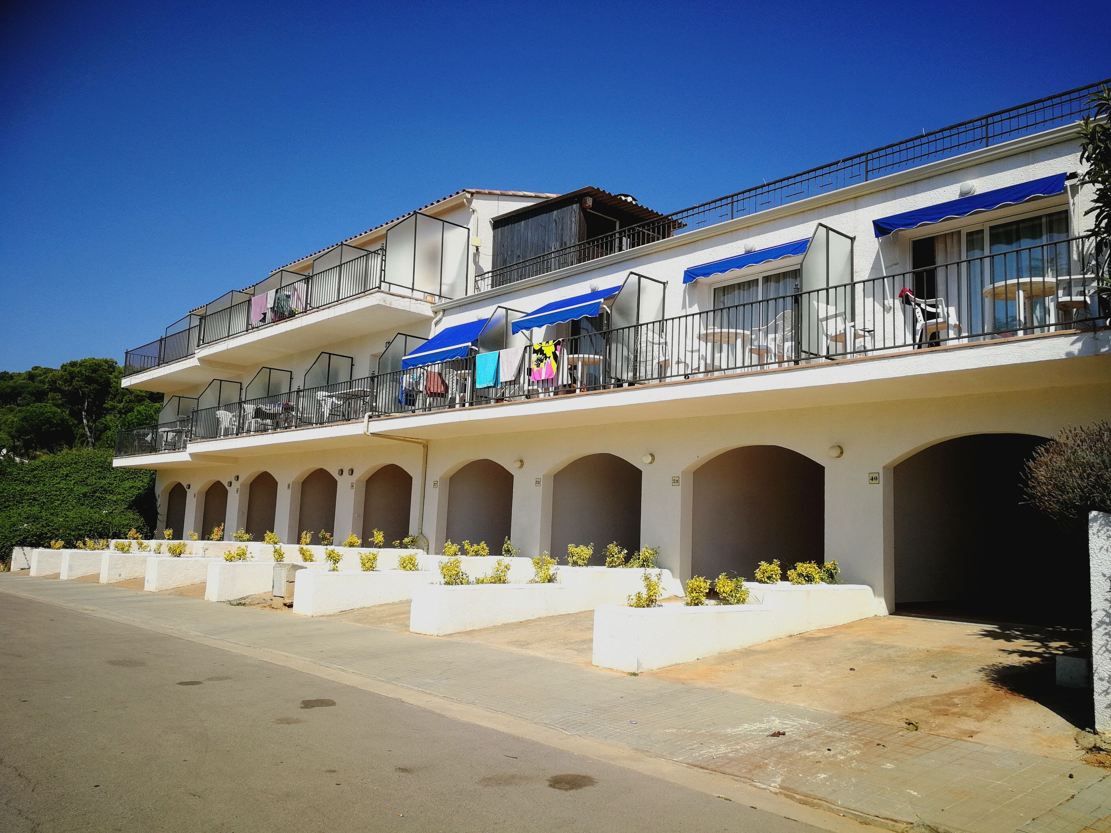 Un hotel de varios pisos con asientos al aire libre y una terraza cubierta.