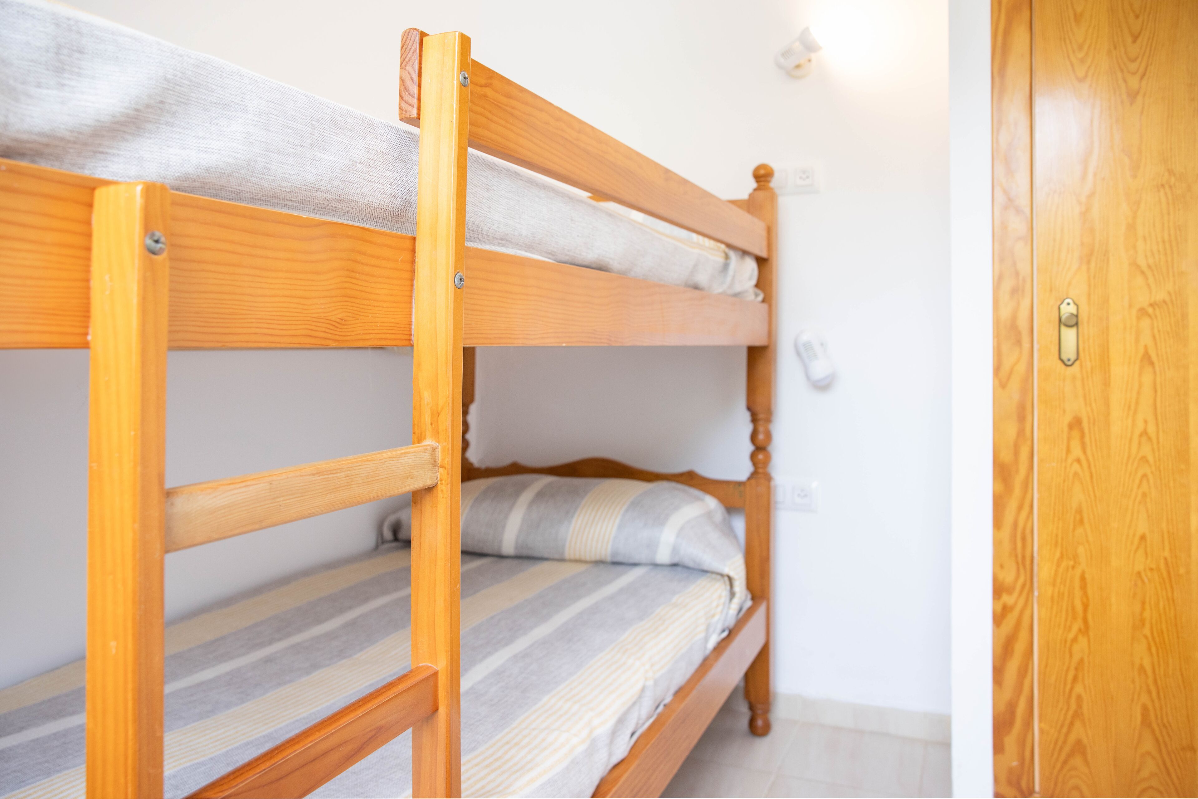 A bunk bed with a wooden frame and a white mattress.