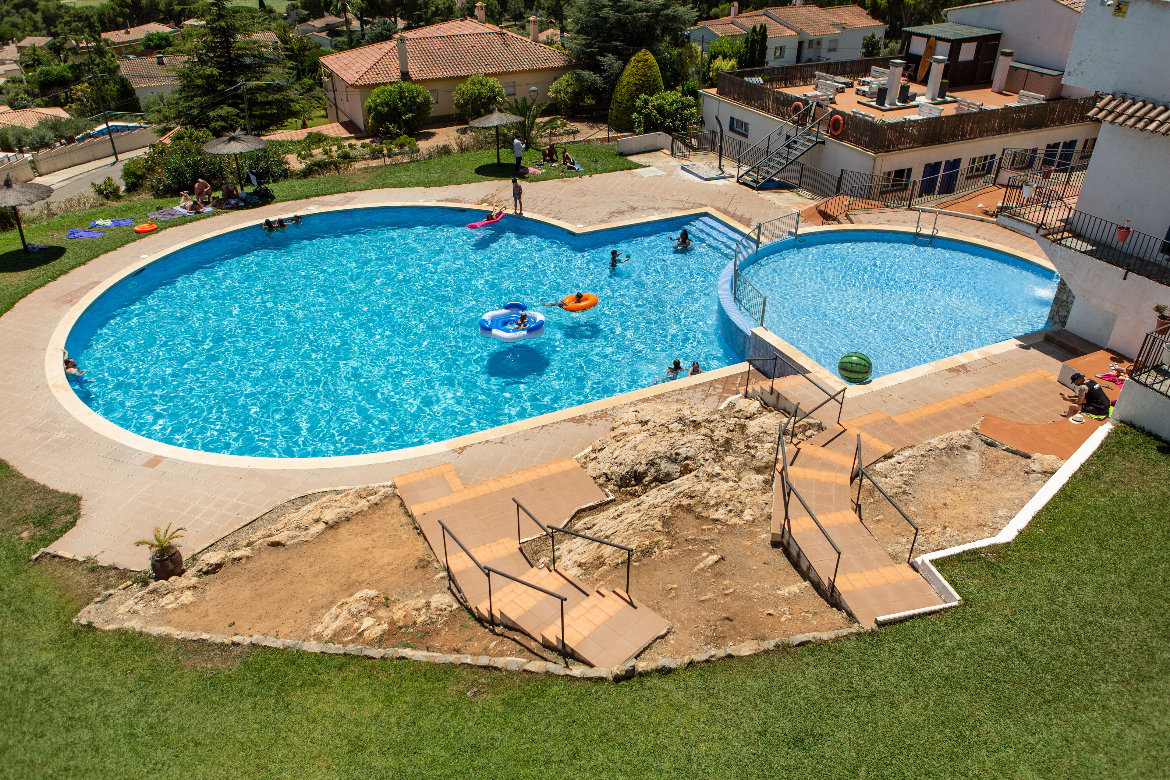 A large outdoor swimming pool with a diving board and steps leading into the water.