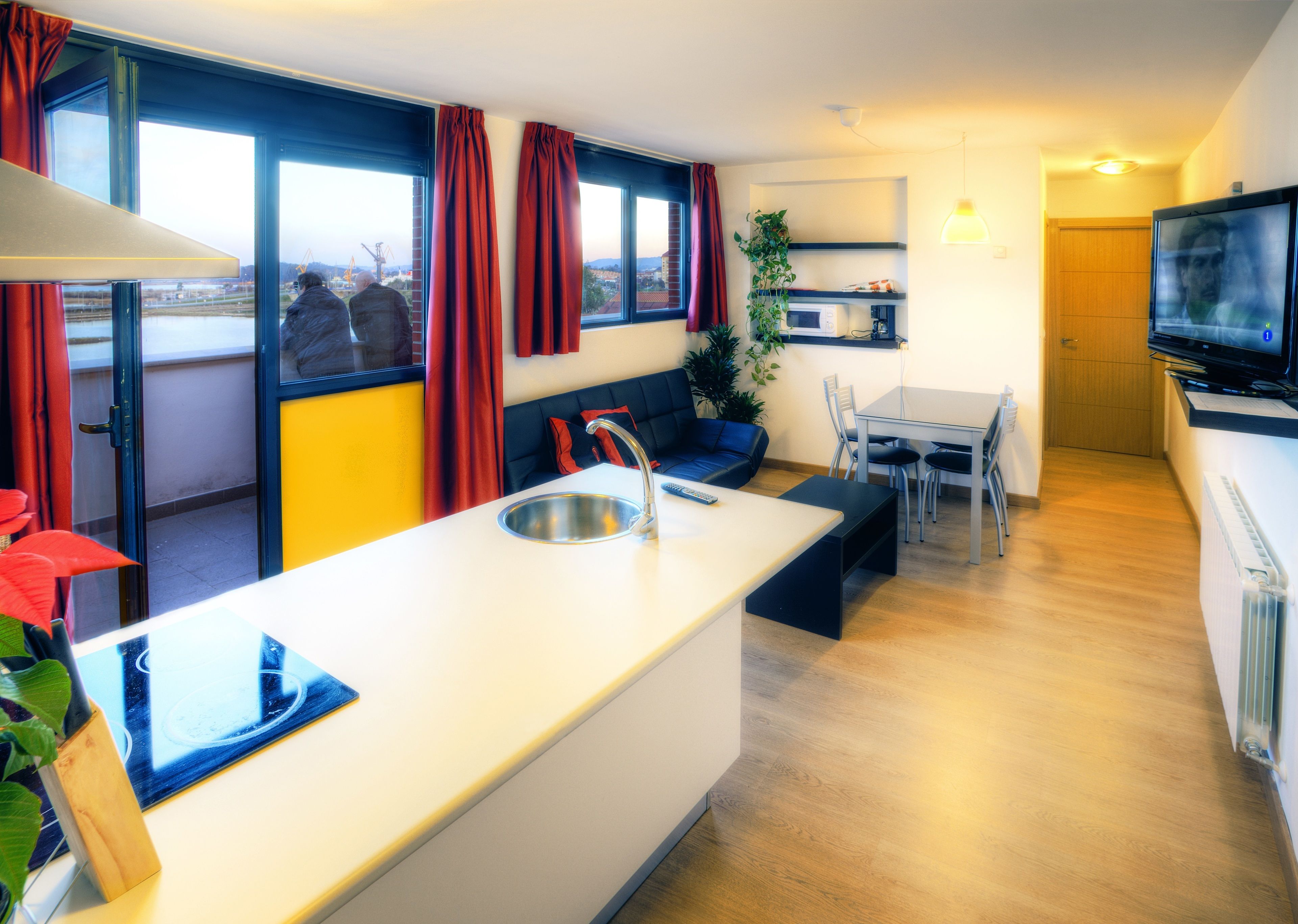 Una cocina moderna con una isla central, un comedor con mesa y sillas, y una zona de estar con sofá.