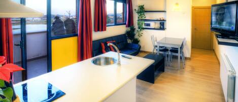 Una cocina moderna con una isla central, un comedor con mesa y sillas, y una zona de estar con sofá.