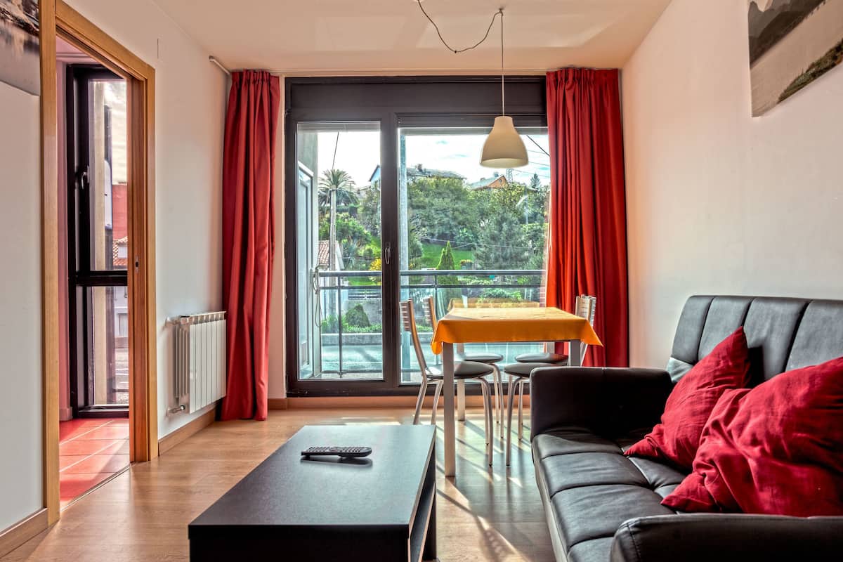 A living room with a sofa, a table, and a view through a glass door.