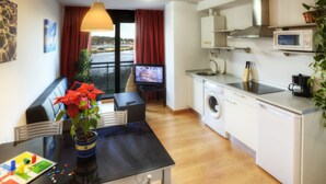 Un espace de vie compact comprenant un coin repas, un lave-linge, un four à micro-ondes et un téléviseur.