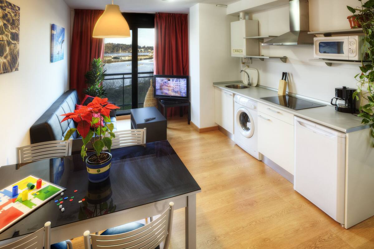 A compact living space with a dining area, a washing machine, a microwave, and a television.
