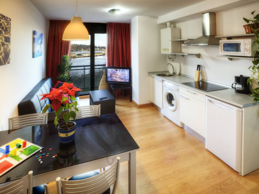 Un espacio habitable compacto con comedor, lavadora, microondas y televisor.