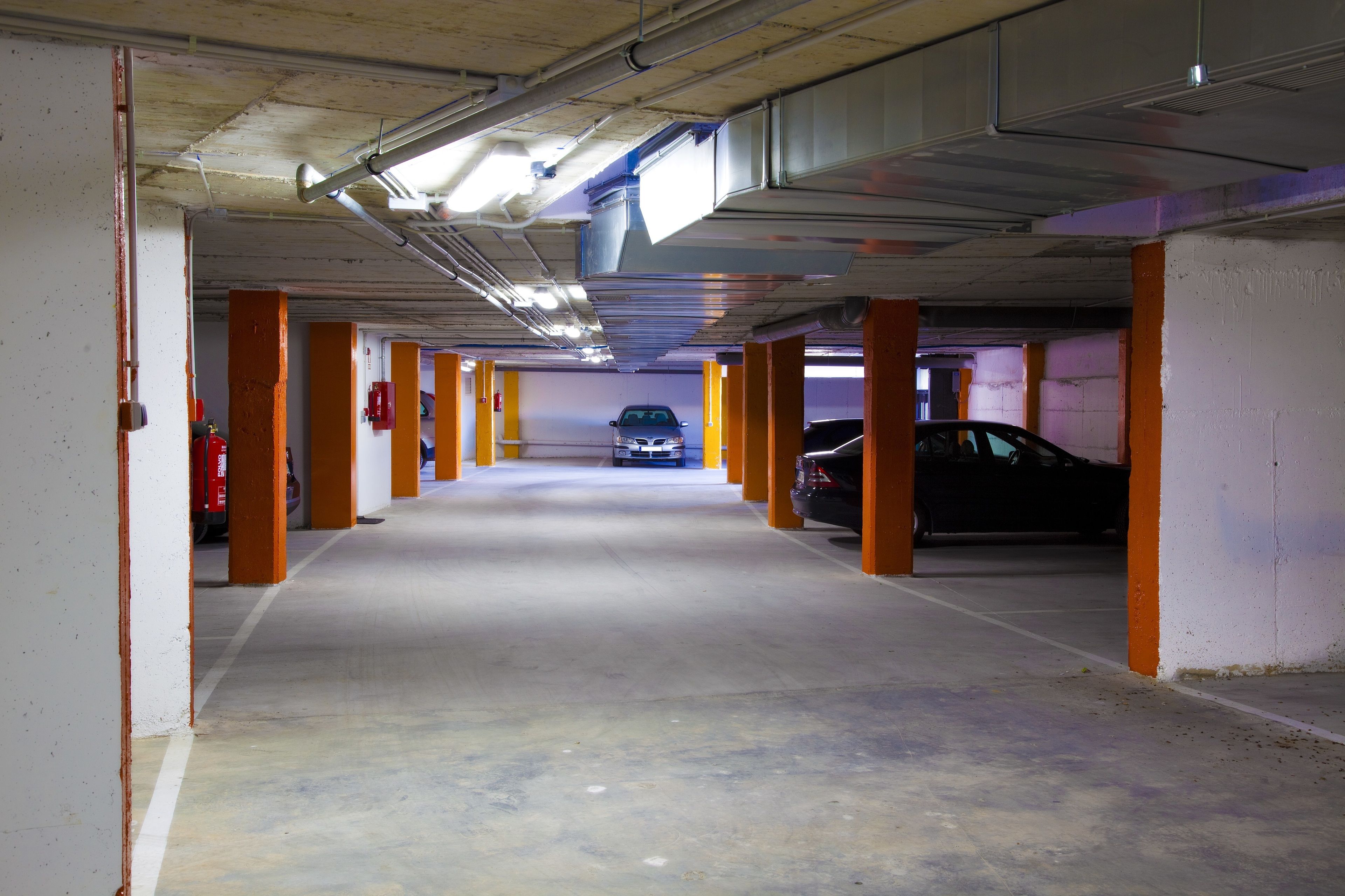 Eine mehrgeschossige Parkgarage mit Betonböden und orangefarbenen Säulen.