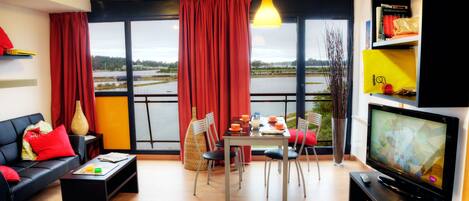 Una sala de estar moderna con comedor, ventanas amplias y televisor.