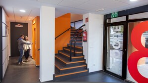 L’entrée d’un hôtel, avec un escalier, un panneau indiquant la sortie et un extincteur fixé au mur.