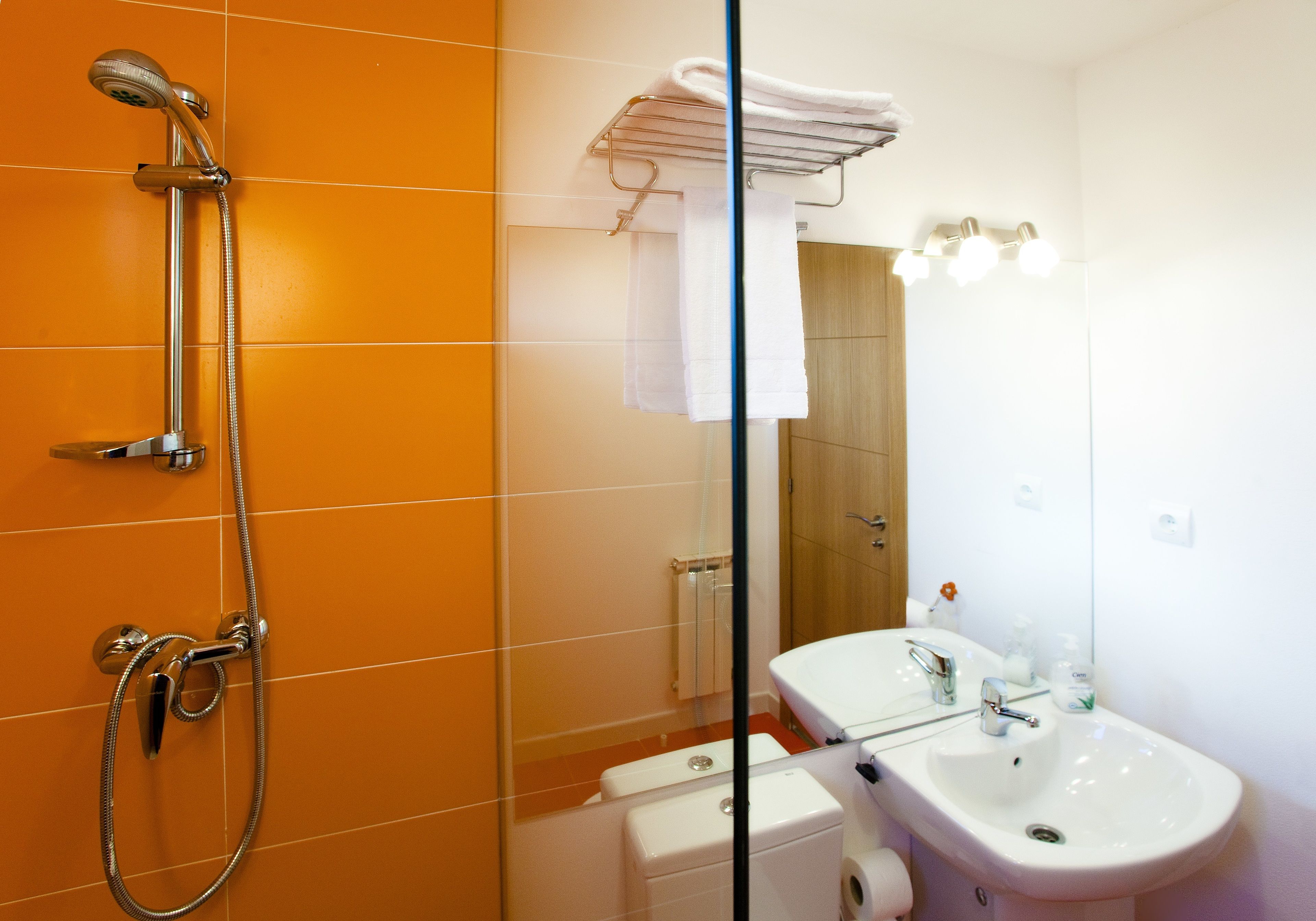 Un baño con ducha, inodoro, lavabo y un perchero para toallas.