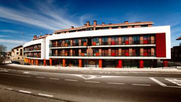 A modern building with a curved facade, multiple balconies, and a prominent red accent wall.
