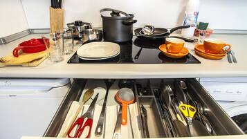 Una cocina con estufa, ollas, sartenes y diversos utensilios.