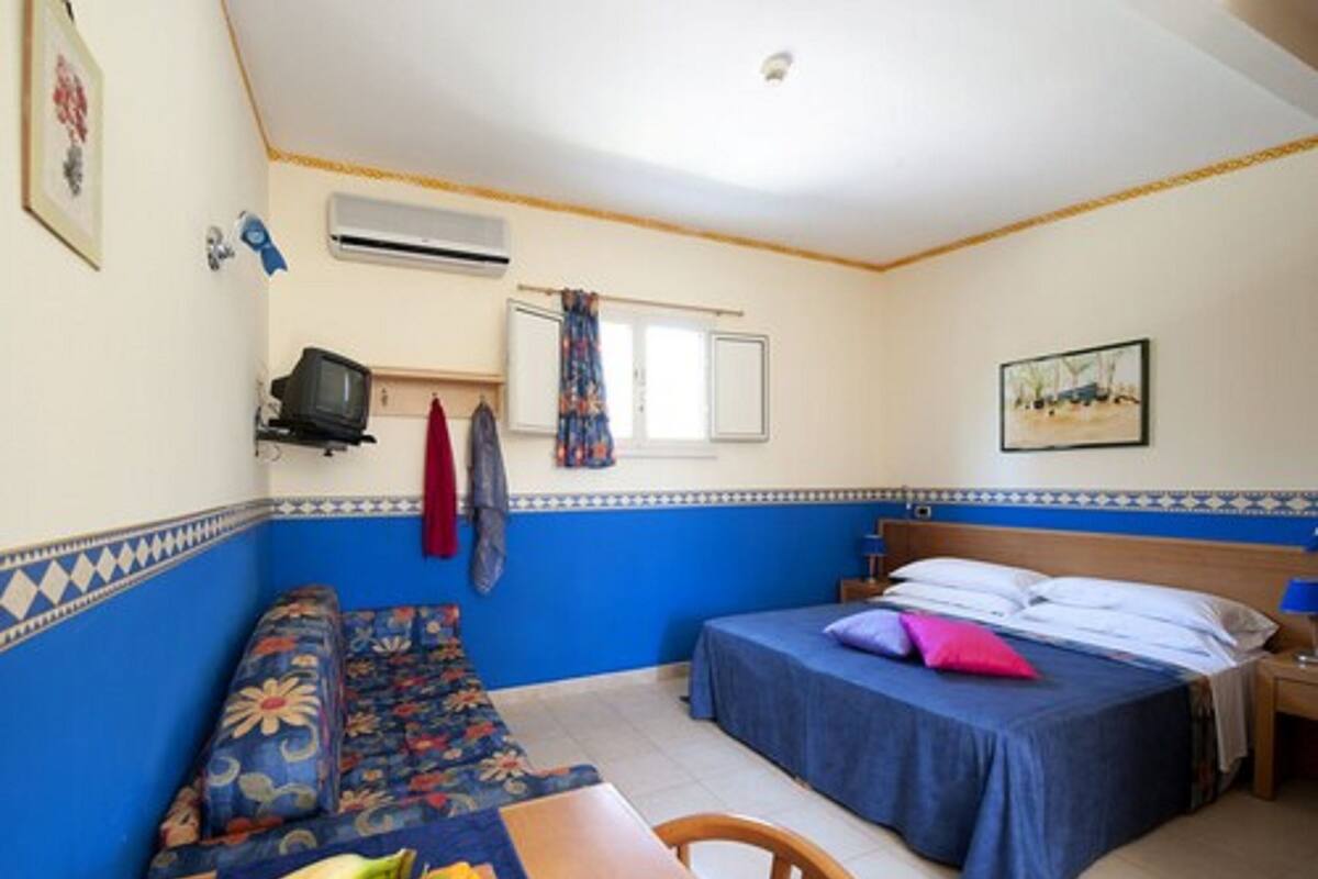 Una habitación con una cama, un sofá, una mesa con fruta y un televisor.