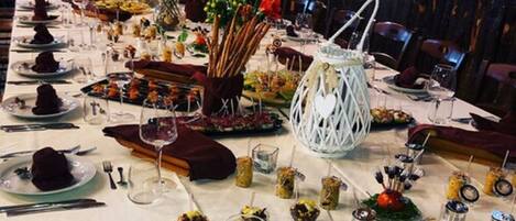 A long dining table set for a formal event, decorated with floral arrangements, candles, and various dishes.