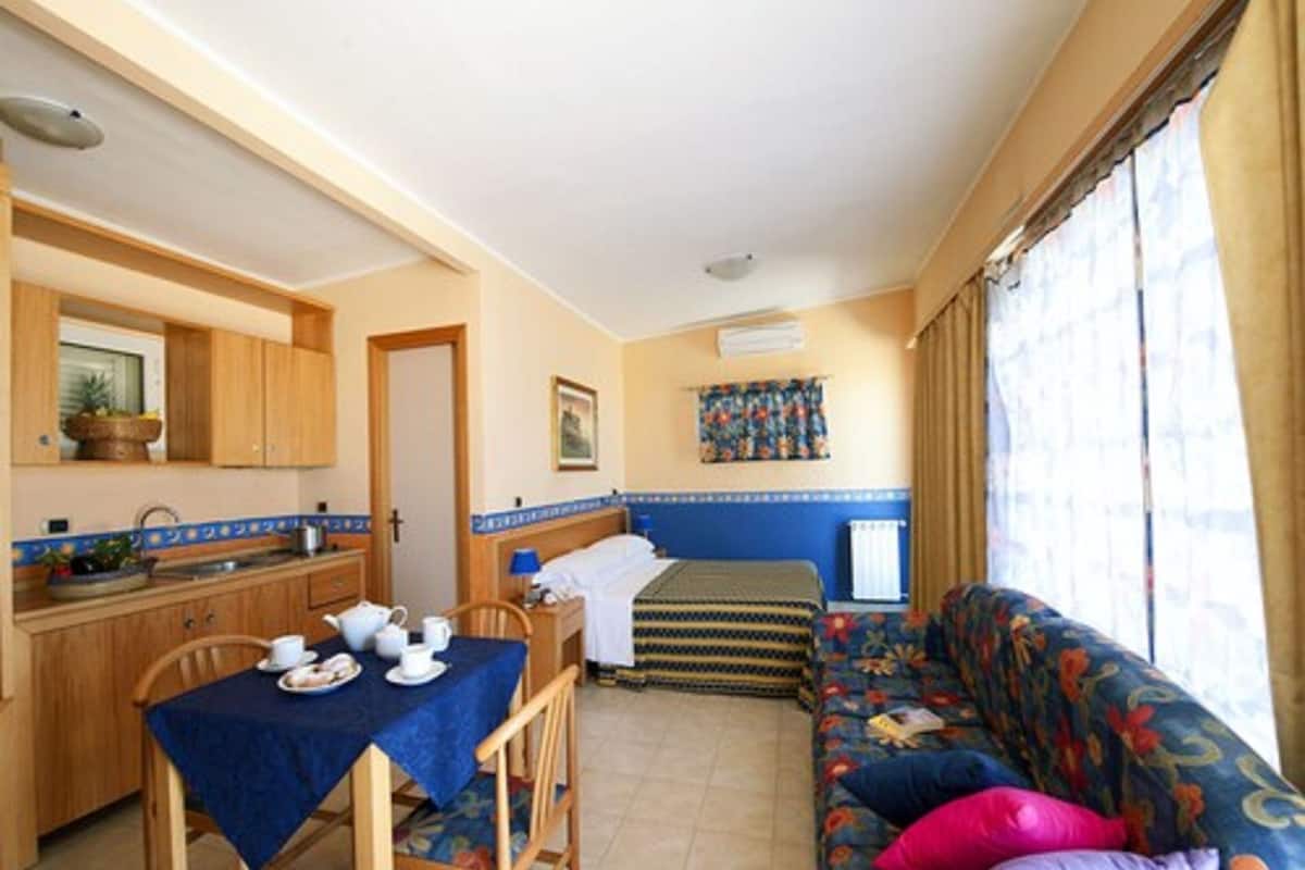 Habitación compacta con kitchenette, comedor y sofá con cojines de colores.