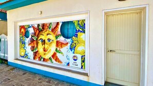 A building with a colorful mural on the wall and a closed door. - Villaggio Turistico Internazionale La Plaja (Catania)
