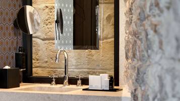 Une salle de bain dotée d’un grand miroir, d’un lavabo moderne et d’articles de toilette.