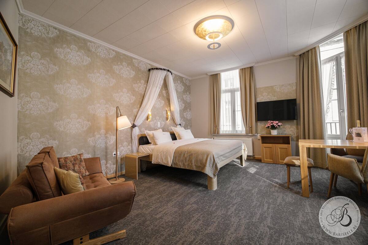 A hotel room with a bed, a sofa, a desk, and a television.