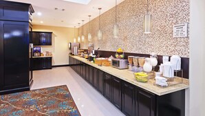 A modern kitchen with a breakfast bar, equipped with various appliances and a sign indicating breakfast hours. - La Quinta Inn & Suites by Wyndham Marshall (Marshall)