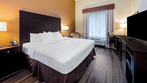 A hotel room with a large bed, bedside lamps, a desk with a chair, a television, and a window with curtains. - La Quinta Inn & Suites by Wyndham Marshall (Marshall)