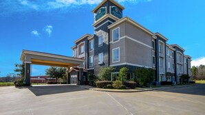 A multi-story hotel with a covered parking area and a prominent clock tower. - La Quinta Inn & Suites by Wyndham Marshall (Marshall)